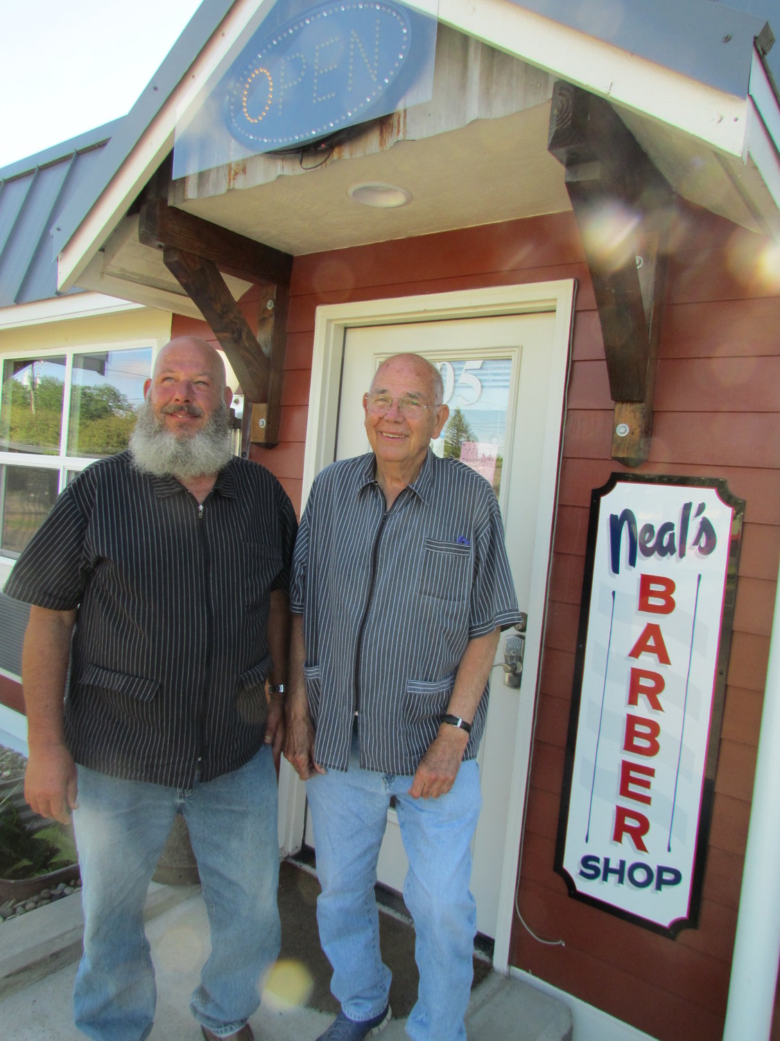NEAL BLOMQUIST (right) and his son Brad have moved their barber shop and have reopened following the COVID-19 mandated closure. The two barbers are working six days a week to catch up with the demand for haircuts.