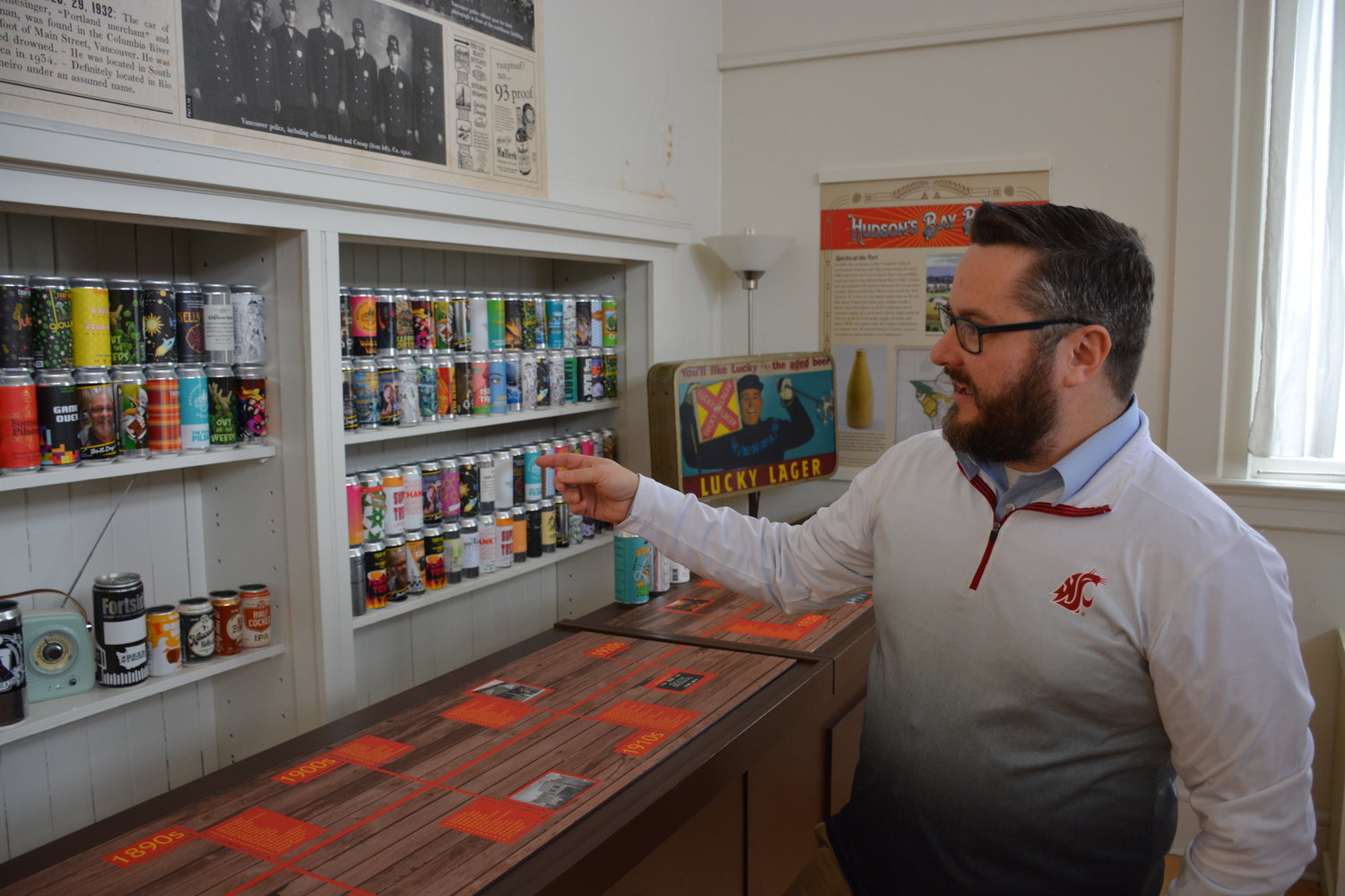 Clark County Historical Society and Museum Executive Director Bradley Richardson stands next to a makeshift bar inside the new exhibit at the Clark County Historical Museum. The cans behind the bar feature many of the different beers offered by Clark County breweries. 