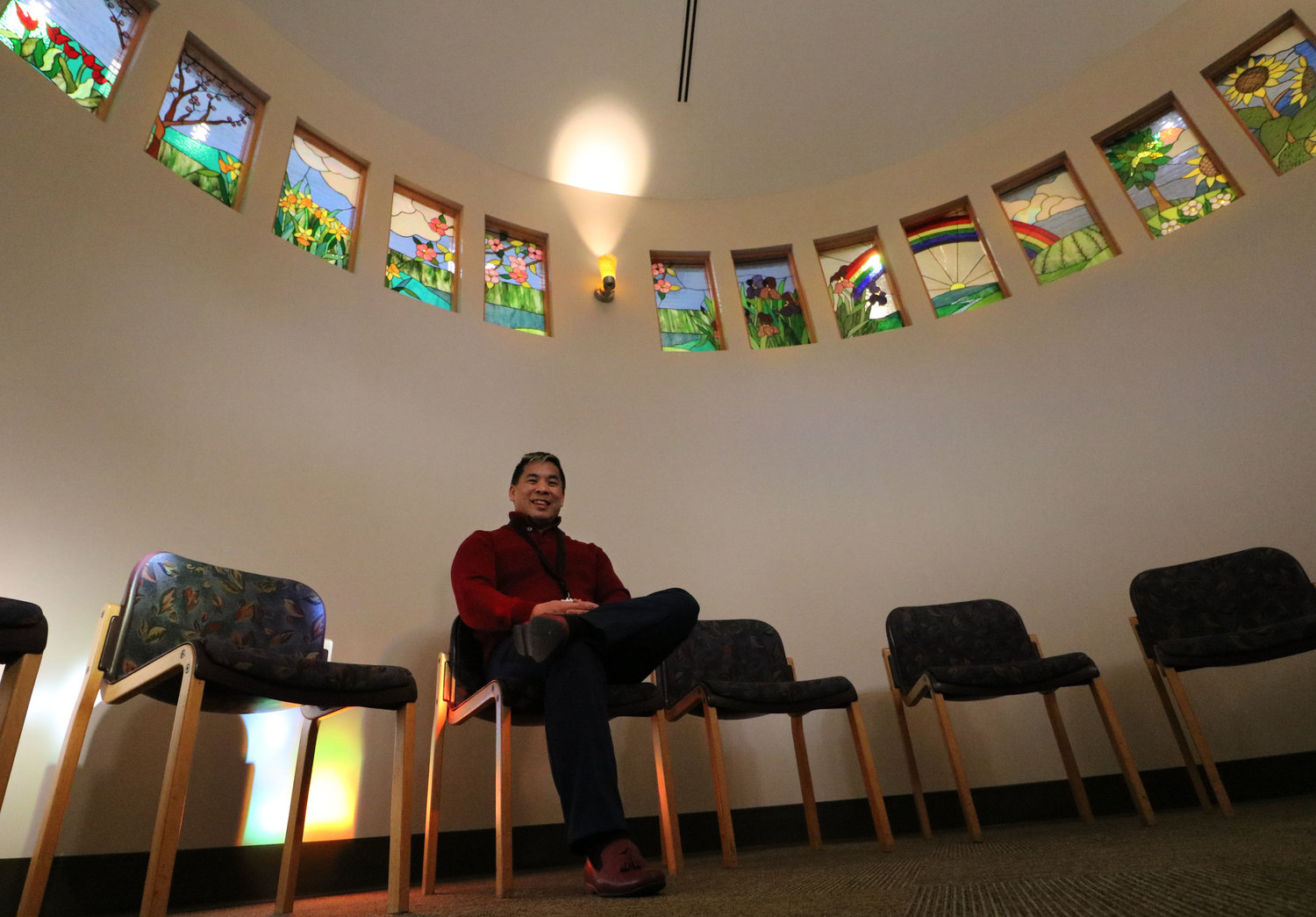 Greg Pang, president and CEO of Community Home Health &amp; Hospice sits in Seasons of Hope Grief Center’s Circle Room last week. The room, which is lined with stained-glass windows, was Pang’s idea. 