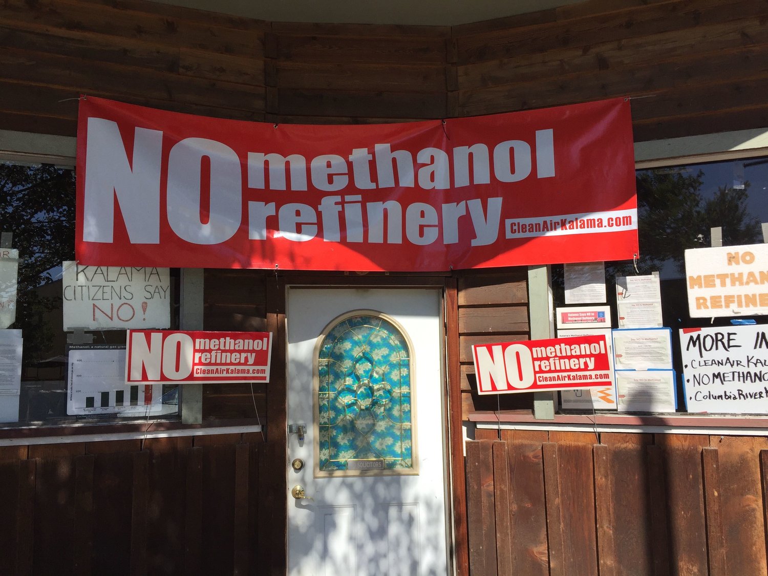 Signs protesting a proposed methanol plant in Kalama are seen in front of an empty storefront in downtown Kalama earlier this year. 