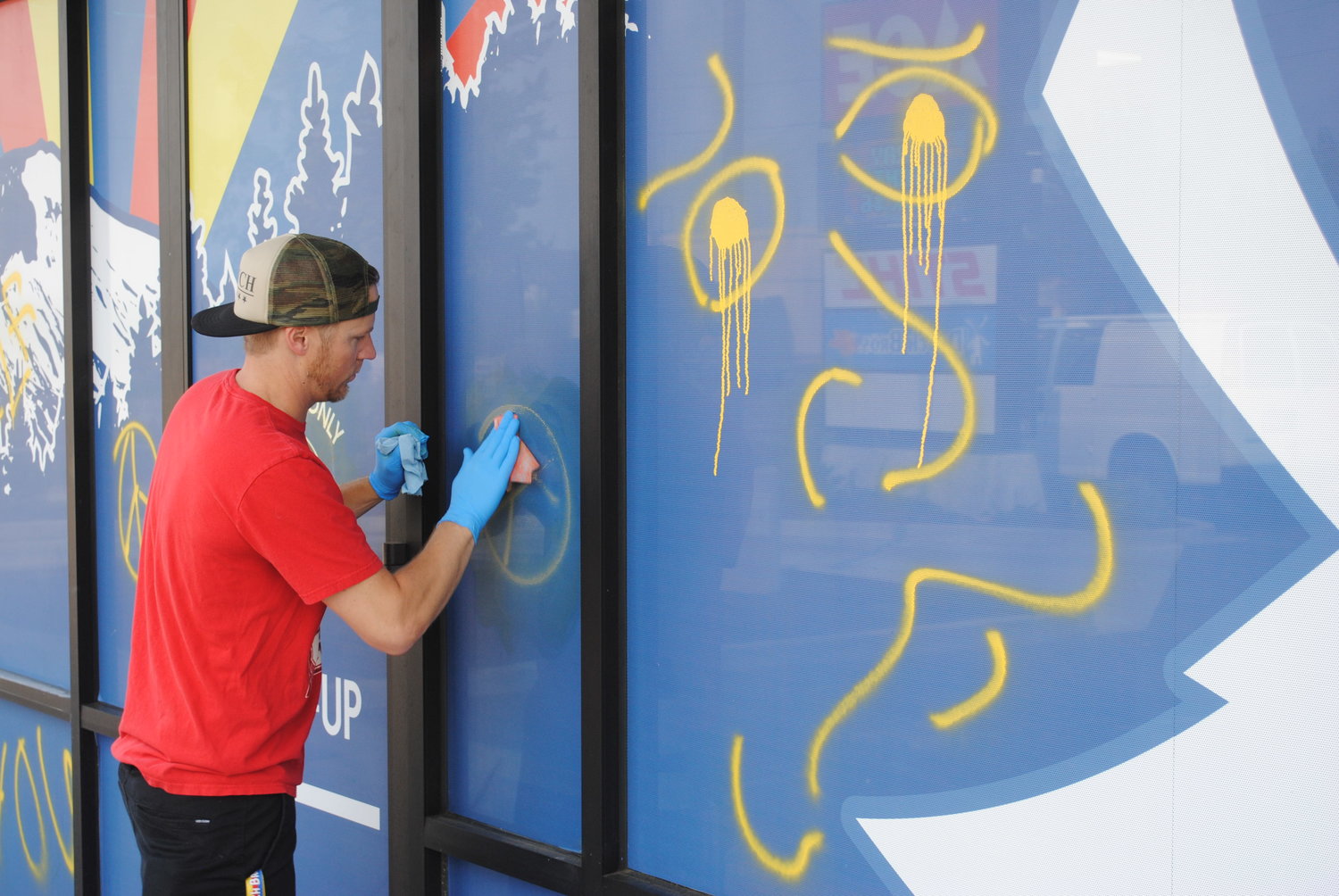 Dutch Bros. owner JJ Herzog scrubs spray paint off the side of his shop. The drive and walk-up coffee shop is one of three buildings vandalized with graffiti in one morning last week. 