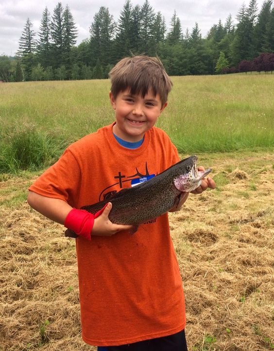 A young angler holds up the trout he just hauled in at Faith Outfitters’ Trout Camp on June 17 