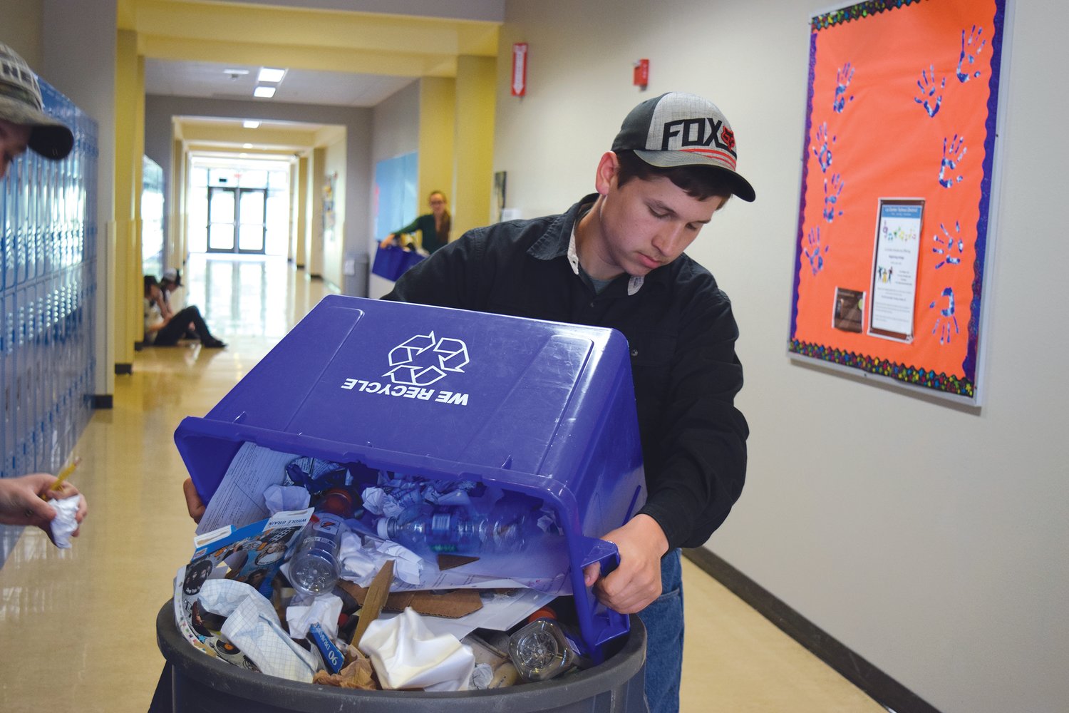 La Center senior Tristan Caywood (above) dumps a recycling bin at the high school. He said the experience of helping make La Center High School recognized as a green school has made him appreciate the environment more.