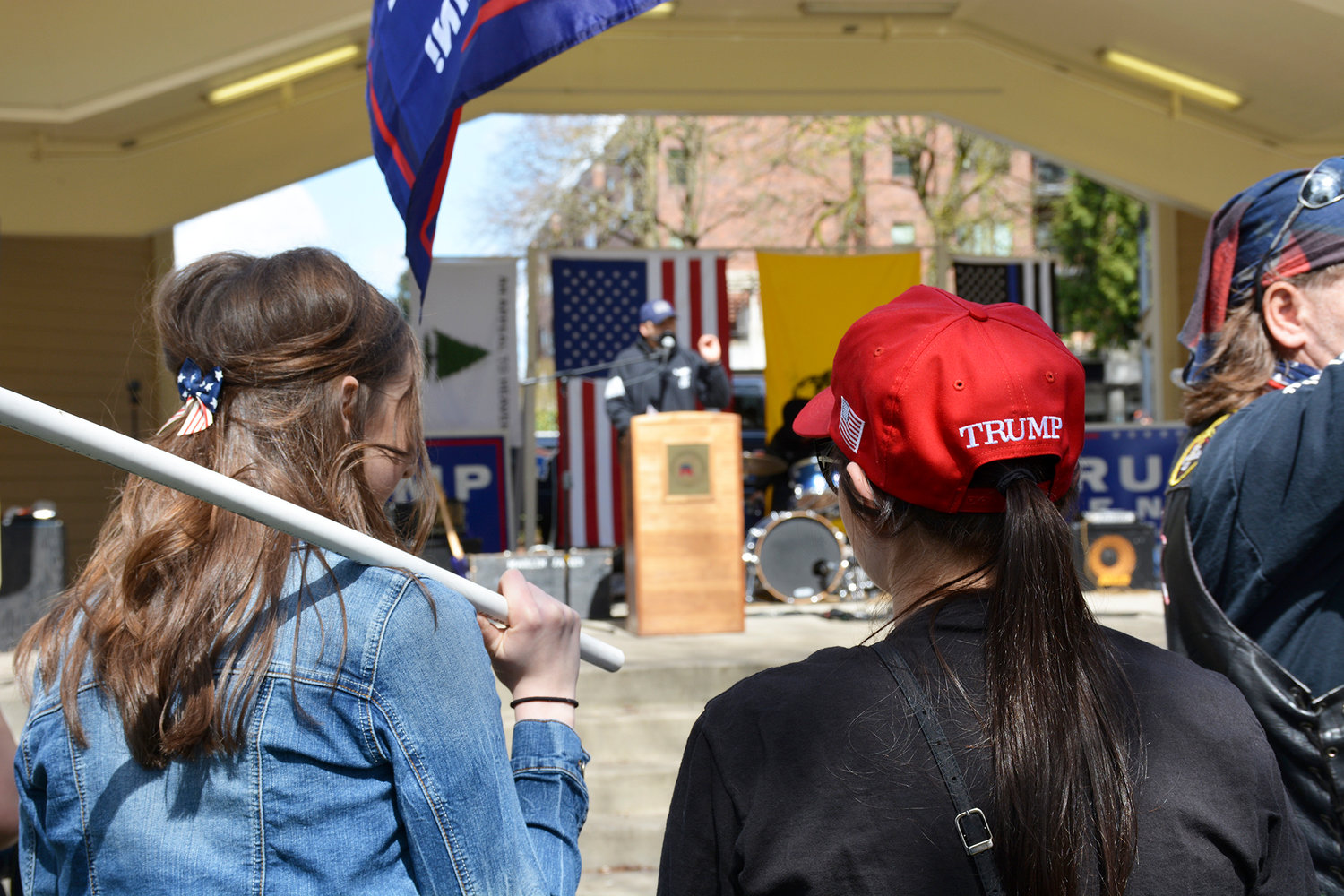 Two younger Trump supporters listen to event organizer Joey Gibson.  