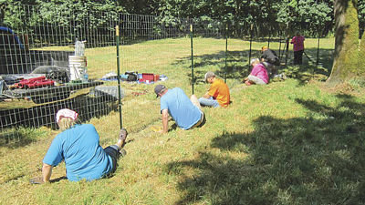 VOLUNTEERS FROM THE Portland-based nonprofit Fences for Fido construct a fence for DJ, a chocolate lab living near Ridgefield with his people, Tracy and Mike Trussler.