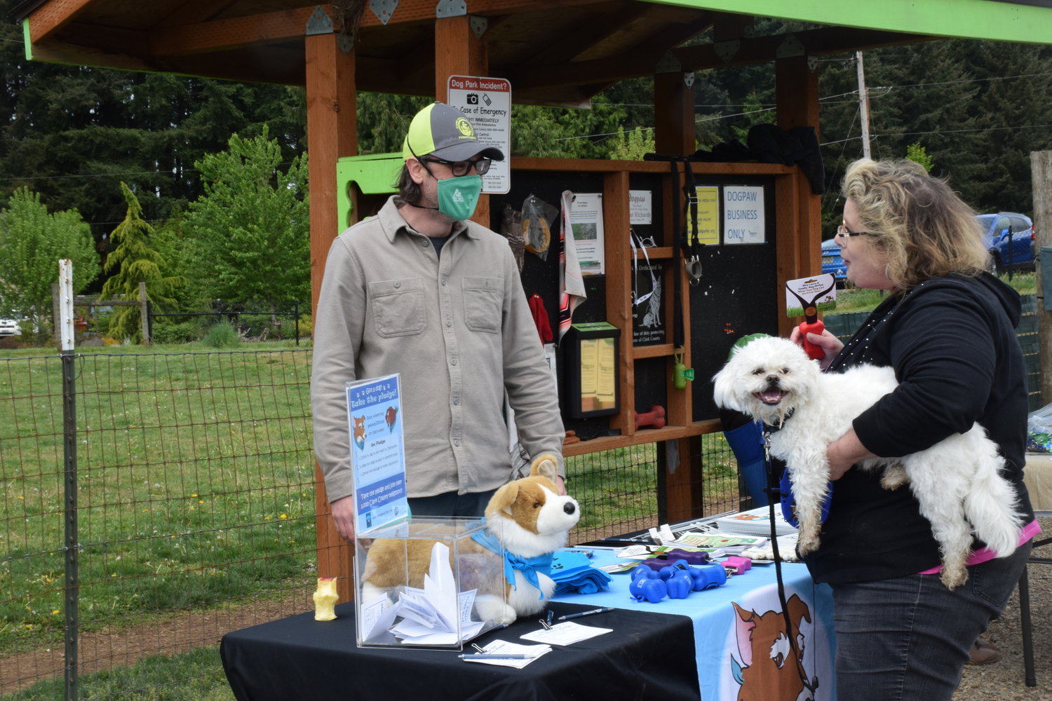 Parkgoer Lorrie Sugich and Jackson hear from Clark County Public Works Clean Water Outreach Specialist Eric Lambert during a cleanup event put on by DOGPAW at Lucky Dog Park in Brush Prairie May 8.