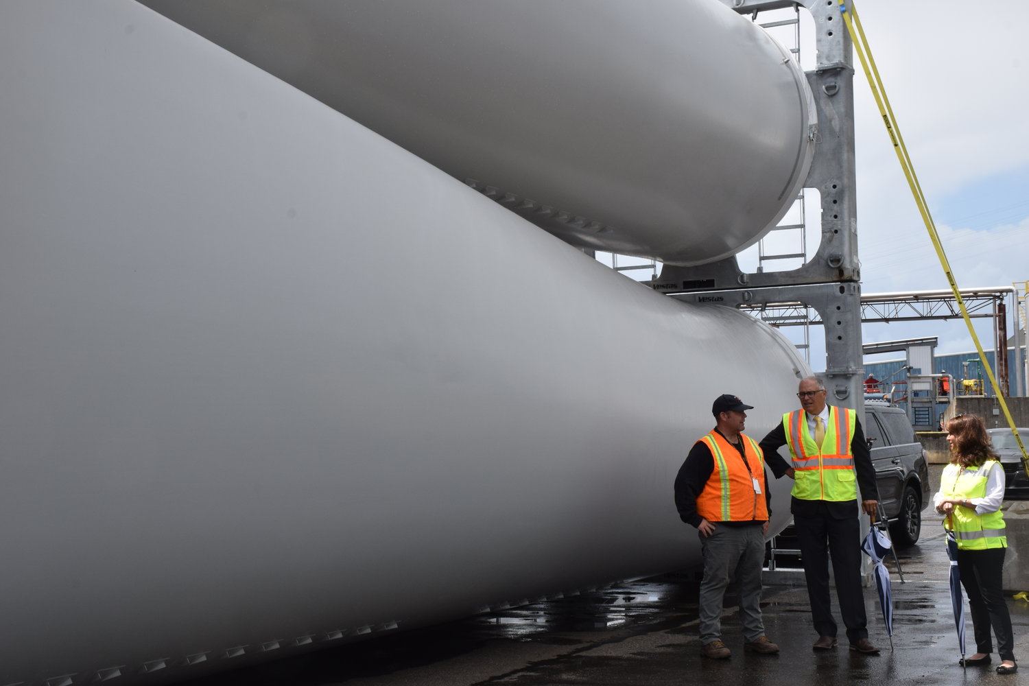 Gov. Jay Inslee, center, stands alongside ILWU Local 4 President Cager Clabaugh and Port of Vancouver CEO Julianna Marler, next to wind turbine blades stored at one of the port’s terminals on June 15.