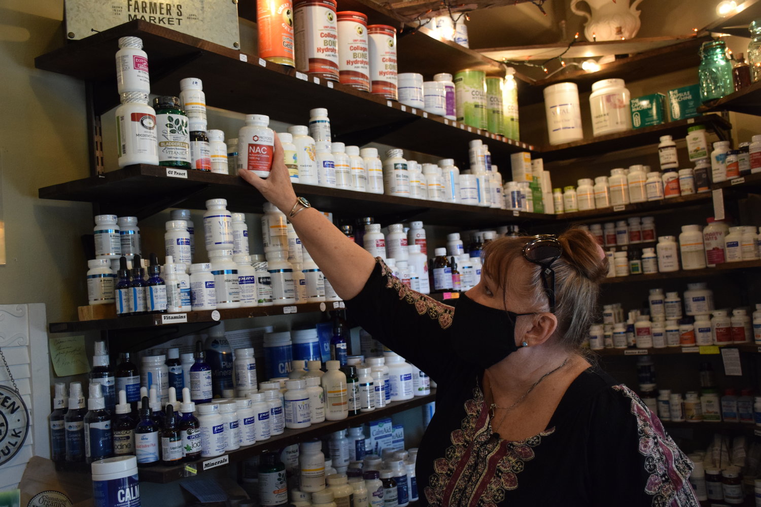Battle Ground Apothecary owner Diana Davidson points out popular supplements her business sells on Sept. 15.