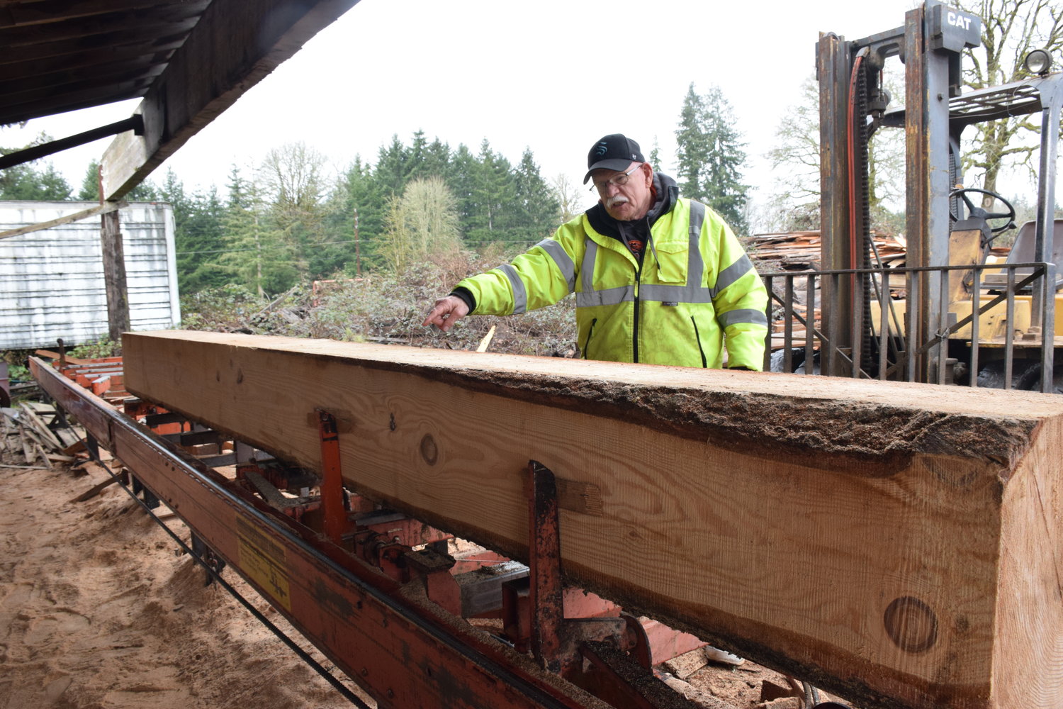 Dollar’s Corner Sawmill operator Pat Lydon examines a log at the sawmill on Feb. 4.