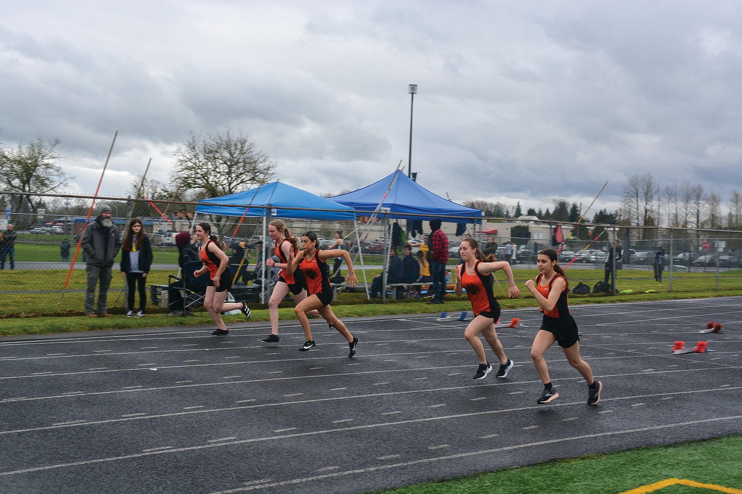 Girls from the Battle Ground track and field team run toward the 100-meter hurdles during their meet against Kelso and Heritage on March 23.