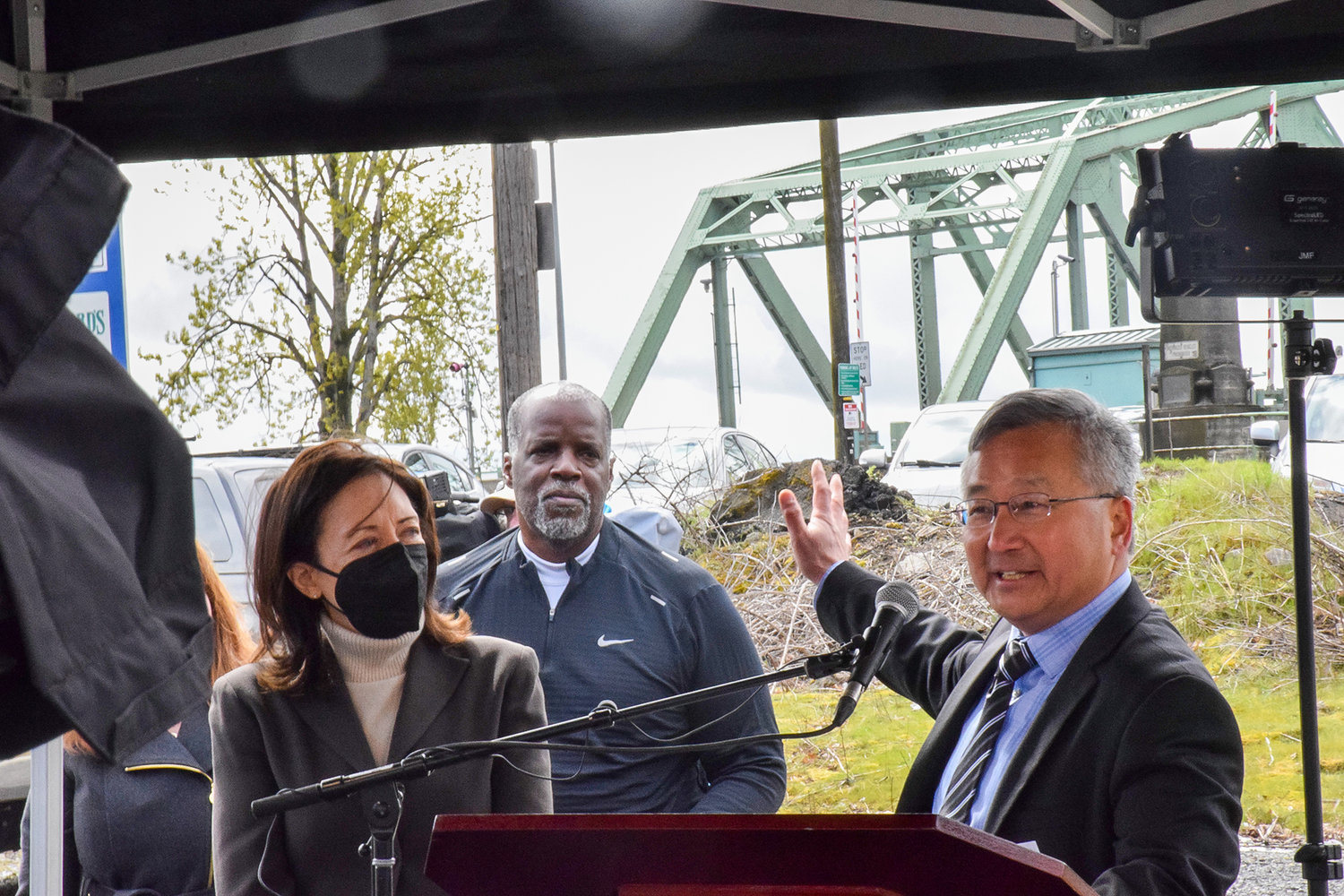 Interstate Bridge Replacement Project Community Advisory Group Member Sam Kim, right, talks about the challenges of a three-hour daily commute as bridge project administrator Greg Johnson and U.S. Sen. Maria Cantwell look on during a press event at the Interstate 5 bridge April 13.