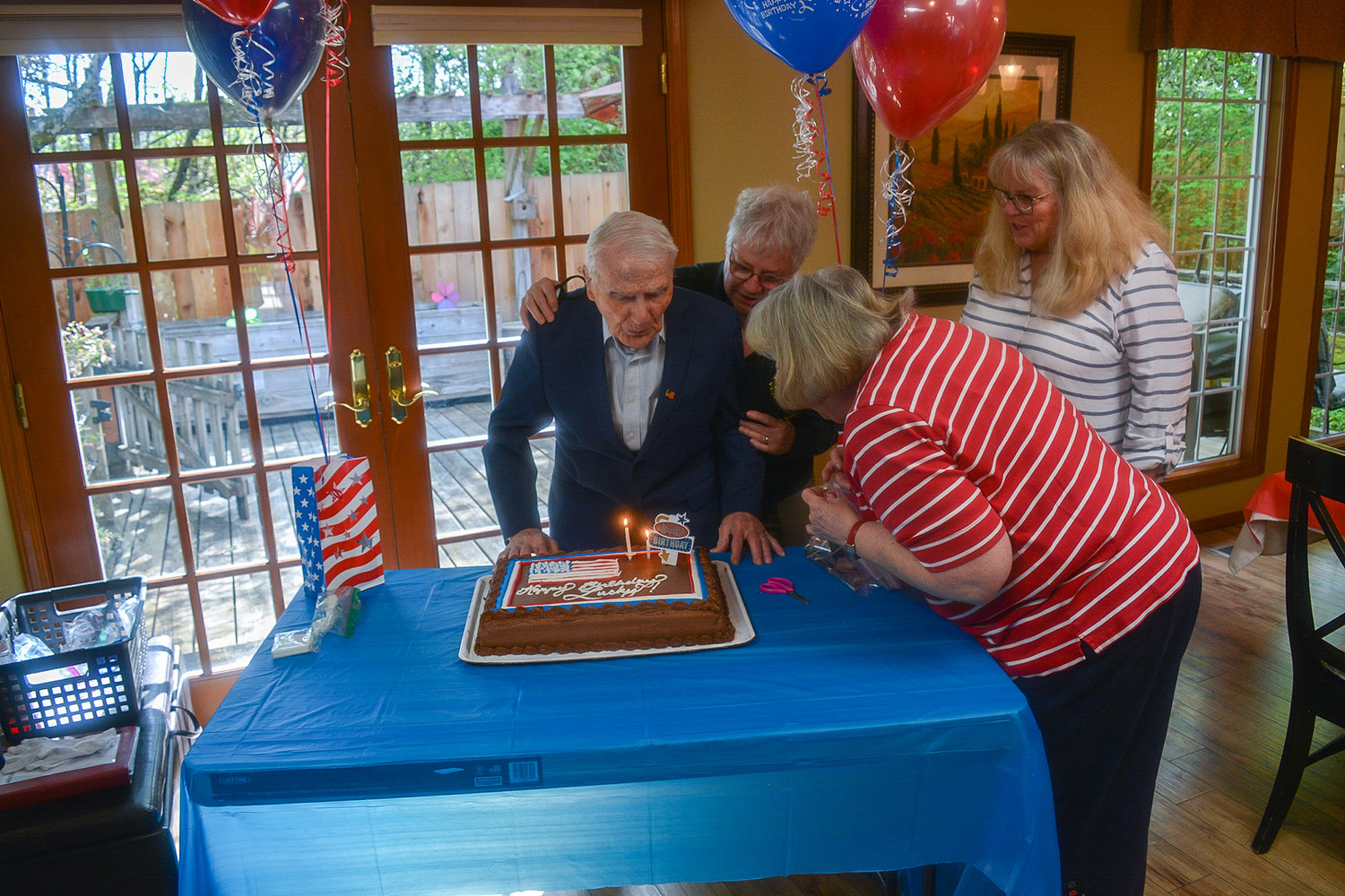 William “Lucky” Mullins blows out the candles on his birthday cake with support from his daughters Jaylene Mullins and Cindy Richert, and their friend Ginnie Bush during his birthday party in Vancouver on May 4.