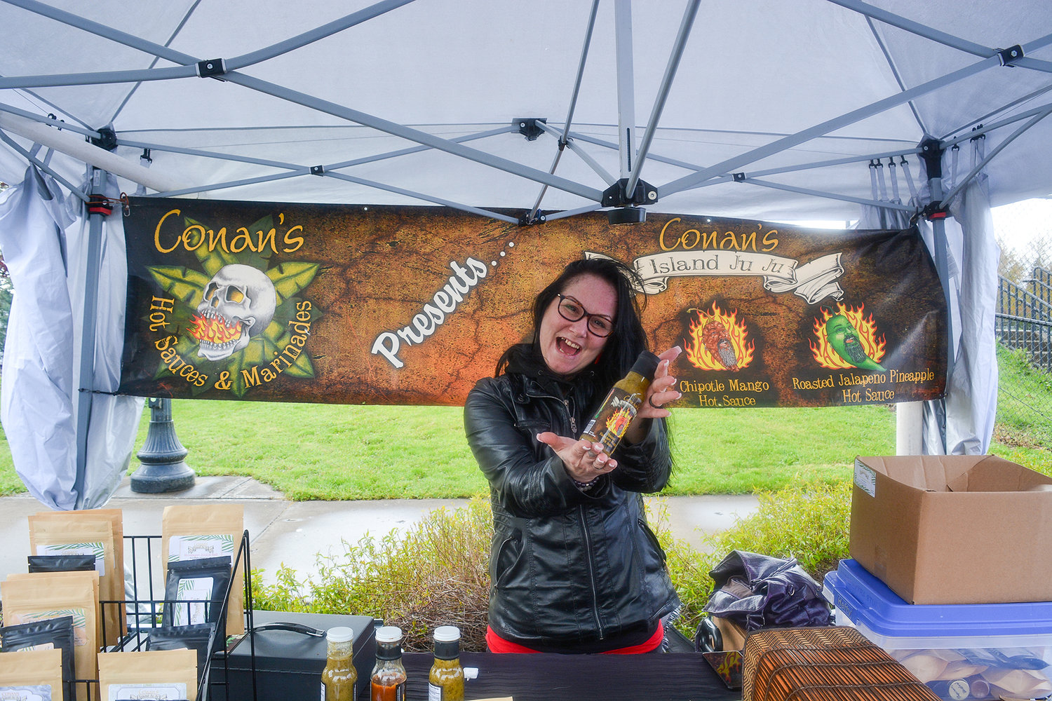 Fawn Hogue presents Conan’s roasted habanero mango hot sauce at the Conan’s Hot Sauces and Marinades booth at the Battle Ground Farmers Market in the parking lot of the community center on May 12.