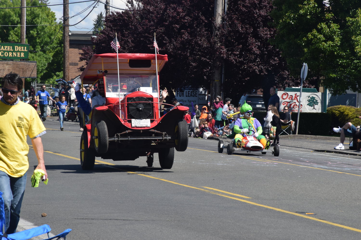 A vintage car pops a wheelie alongside a clown during the 2022 Parade of Bands in Hazel Dell on May 21.