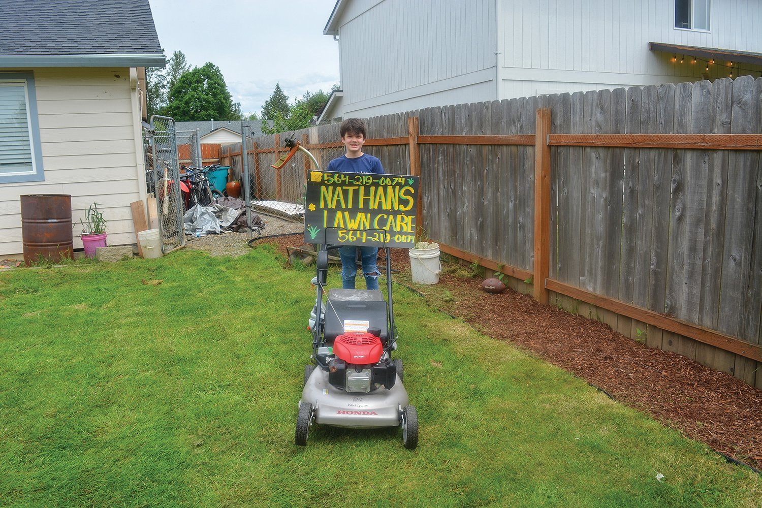 Nathan Pascu is pictured with his lawnmower and weed whacker at his grandmother’s house with his Nathan’s Lawn Care sign on June 1.