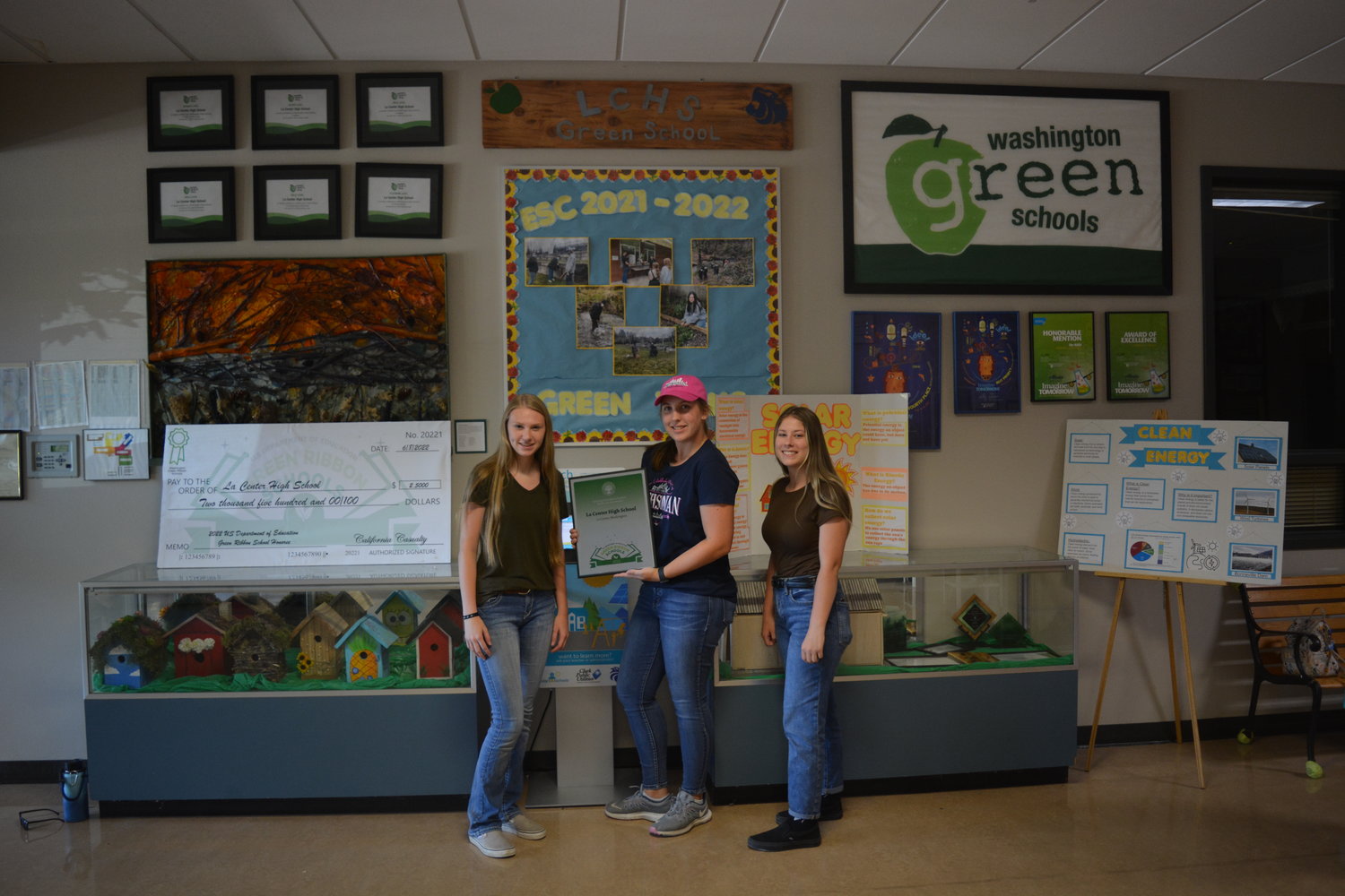 Officers from La Center High School’s Environmental Action Team show off their Green Ribbon Award plaque in front of the team’s display at the school on Aug. 2.