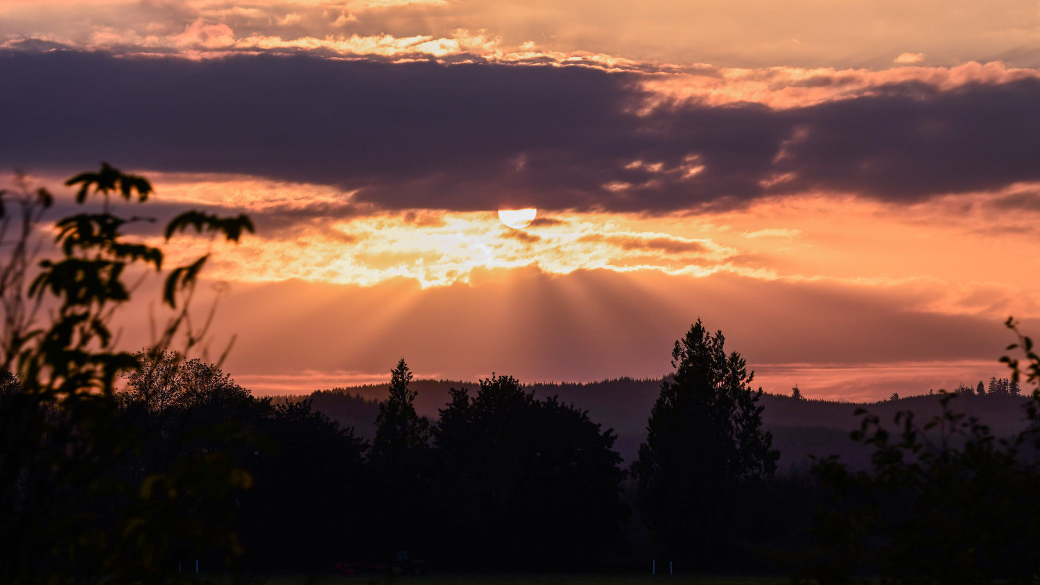 Rays of light shine through clouds over the Willapa Hills as the sun sets.