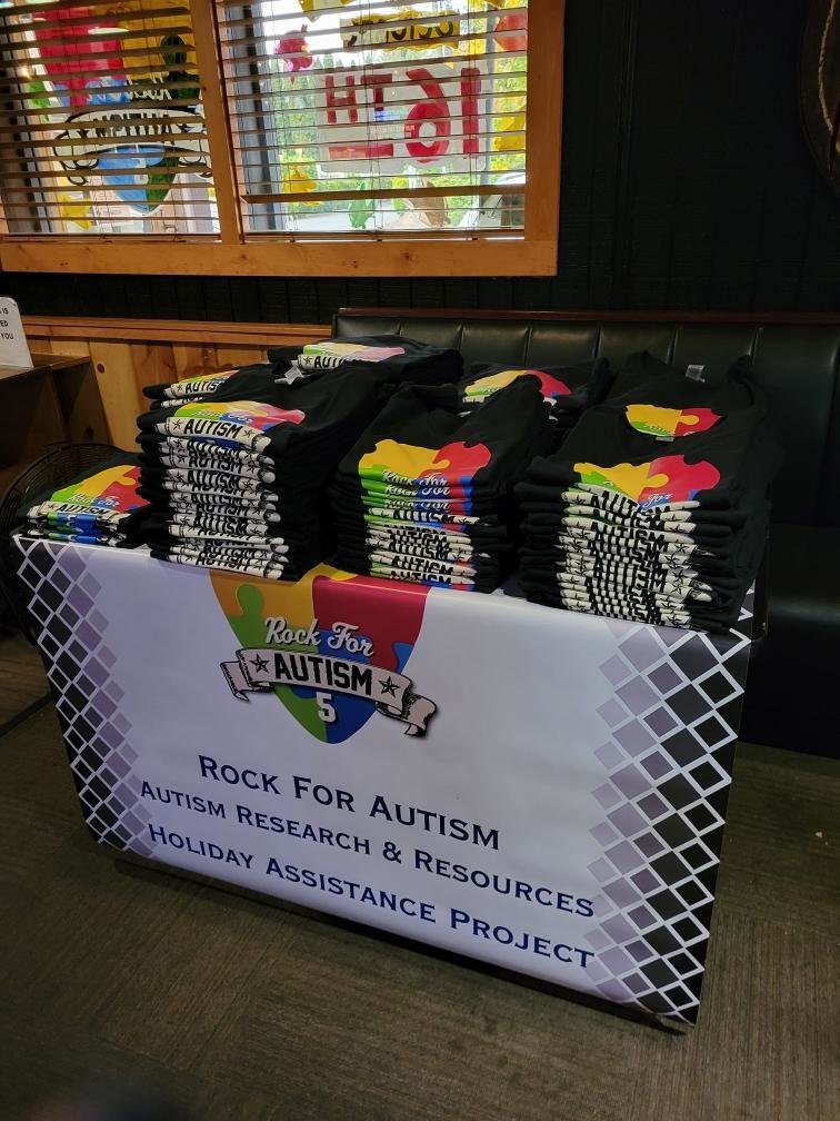 A table of T-shirts sits at a previous Rock For Autism fundraiser.