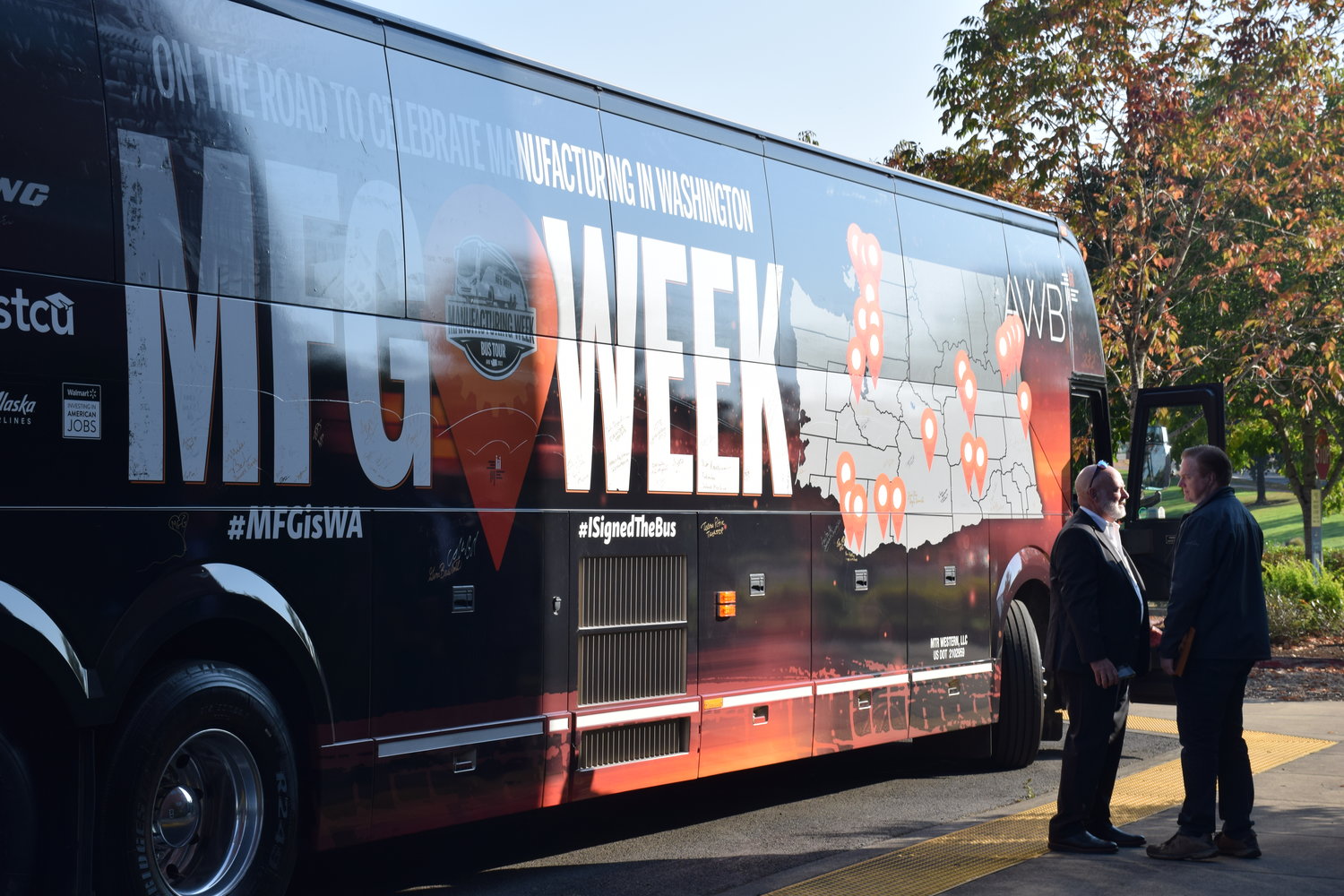 Clark College Center of Excellence for Semiconductor and Electronics Manufacturing Director Carl Douglas, left, speaks with Association of Washington Business President Kris Johnson in front of the association’s “Manufacturing Week” bus during a stop at the college’s Columbia Tech Center campus on Oct. 10.