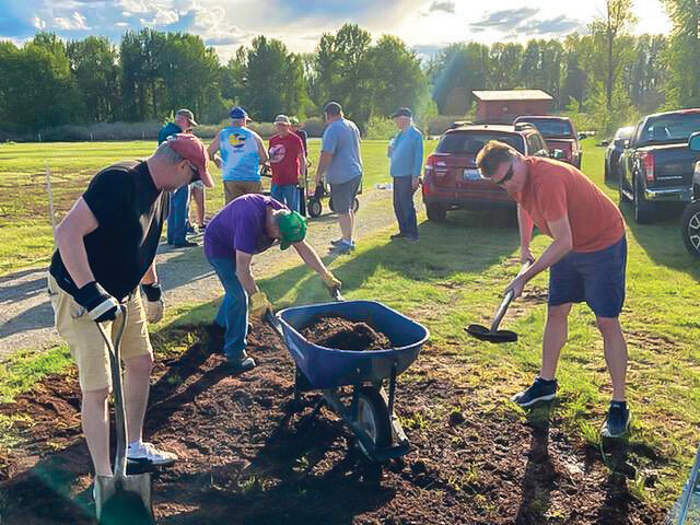 Members of the Ridgefield Lions Club apply soil to level out a field designated for the organization’s Sausage Festival.