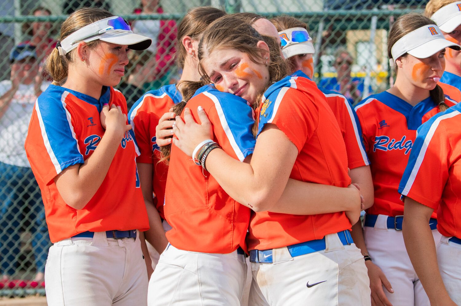 Ridgefield athletes embrace after losing in a state title game against North Kitsap at Carlon Park in Selah on Saturday, May 27.