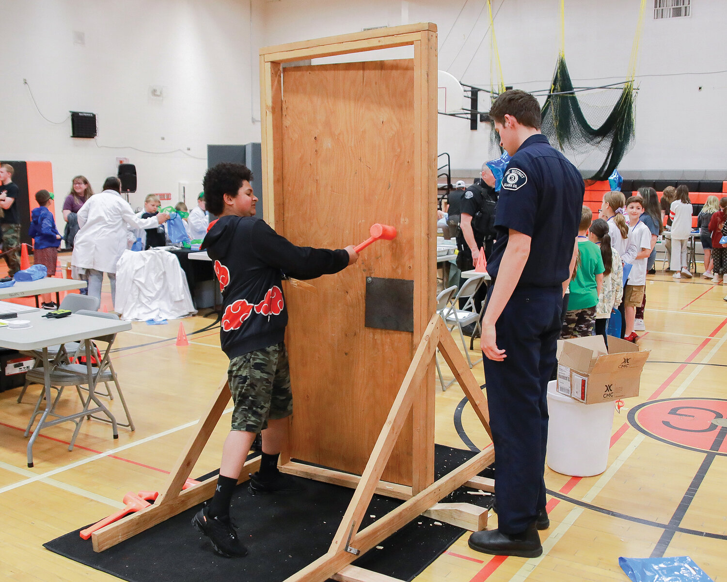 A student from Daybreak Primary School breaks through a door at the Clark County Fire District 3 table at the fourth grade career fair at Battle Ground High School on Tuesday, May 30.