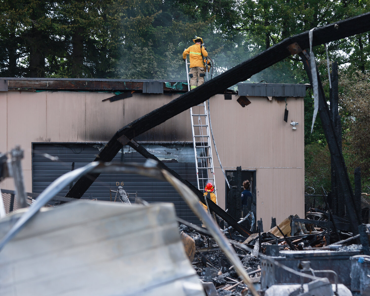 A firefighter checks a building at around 10:05 a.m. on Wednesday, June 7, as smoke rises from the roof following a two-alarm fire in Salmon Creek that destroyed at least seven businesses.