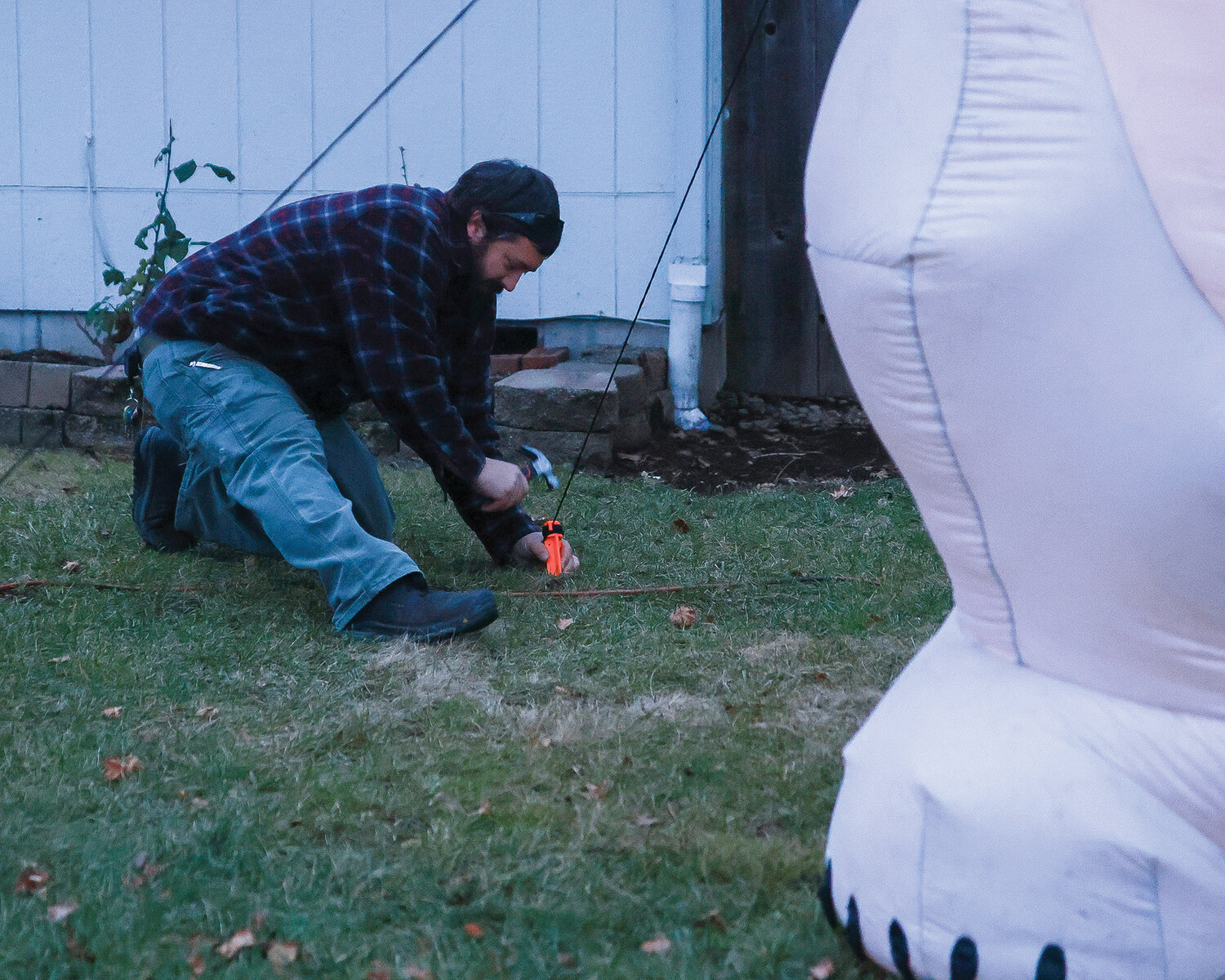 Toby Schultz hammers stakes into the ground as he finishes up the tradition and sign of Christmas for the Schultz family, their 14-foot tall inflatable polar bear.